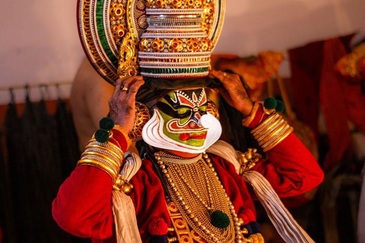 Kathakali performer in full green face makeup, white chutti frame and golden headdress
