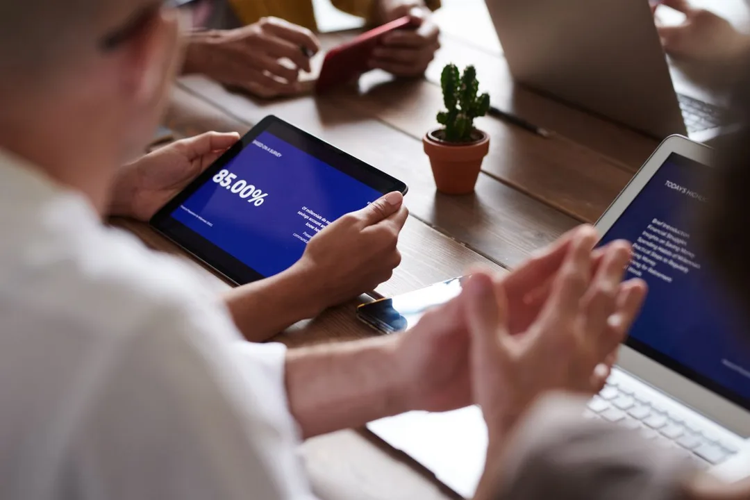 Colleagues reviewing figures together on tablets at a meeting table