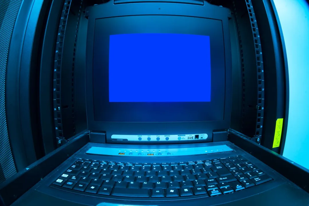 Laptop open inside a server room rack aisle