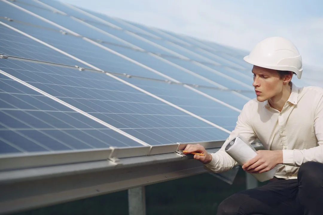 Technician in a hard hat inspecting solar panels