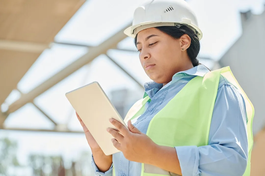 Site engineer in a hard hat checking a tablet