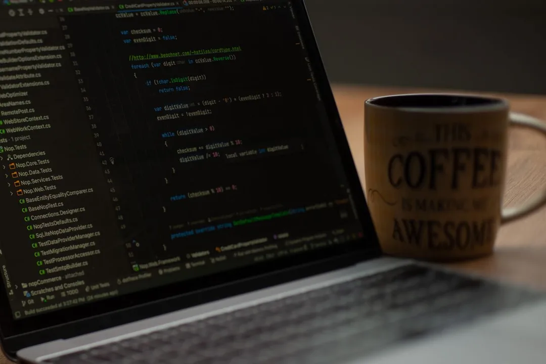 Laptop showing application code beside a coffee mug