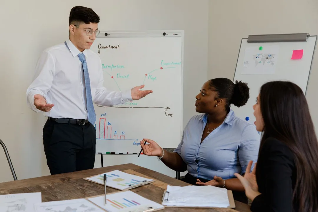 Consultant at a whiteboard walking two colleagues through a process