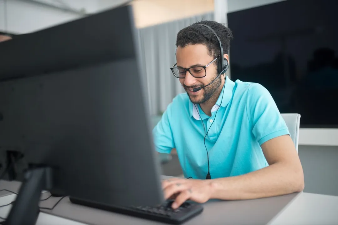 Support engineer wearing a headset, working at a computer