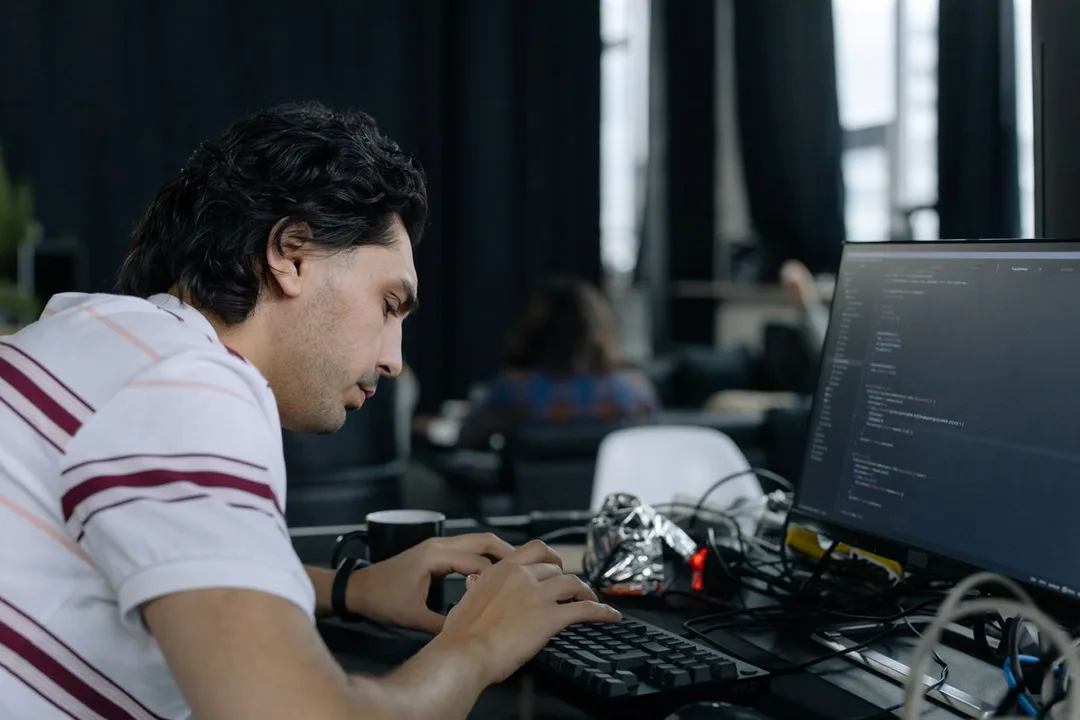 Developer working at a multi-monitor desk in a shared office