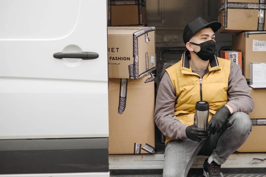 Delivery worker beside a van loaded with cartons